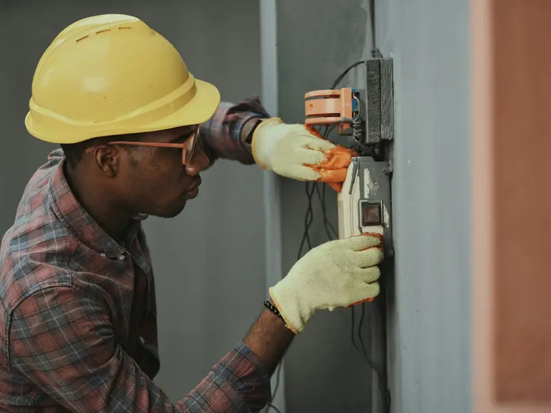 An electrician in a hard hat checking the wiring